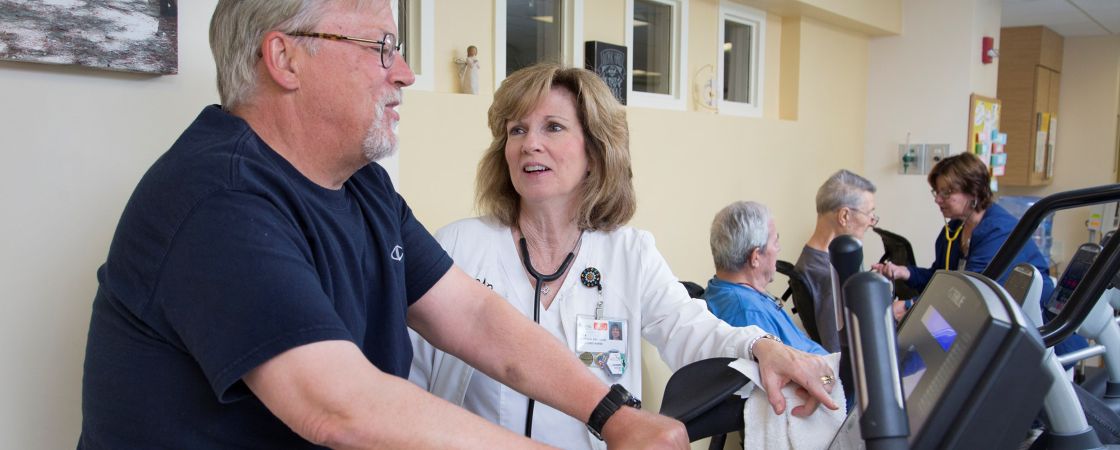 Doctor assisting patient using exercise equipment