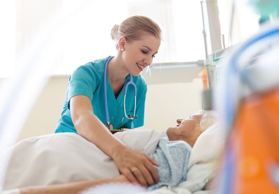 Doctor tucking in elderly patient in hospital bed